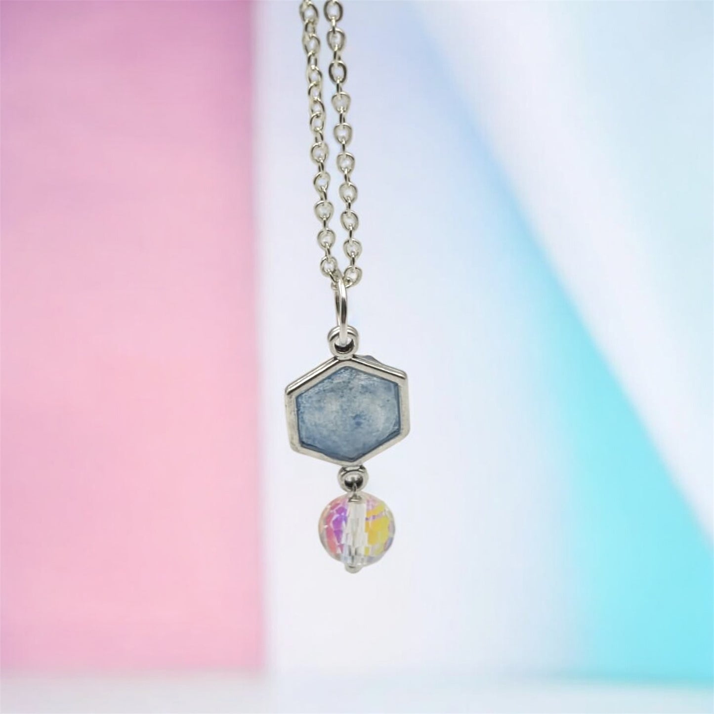 Necklace with a hexagonal pendant and colorful bead on a gradient background