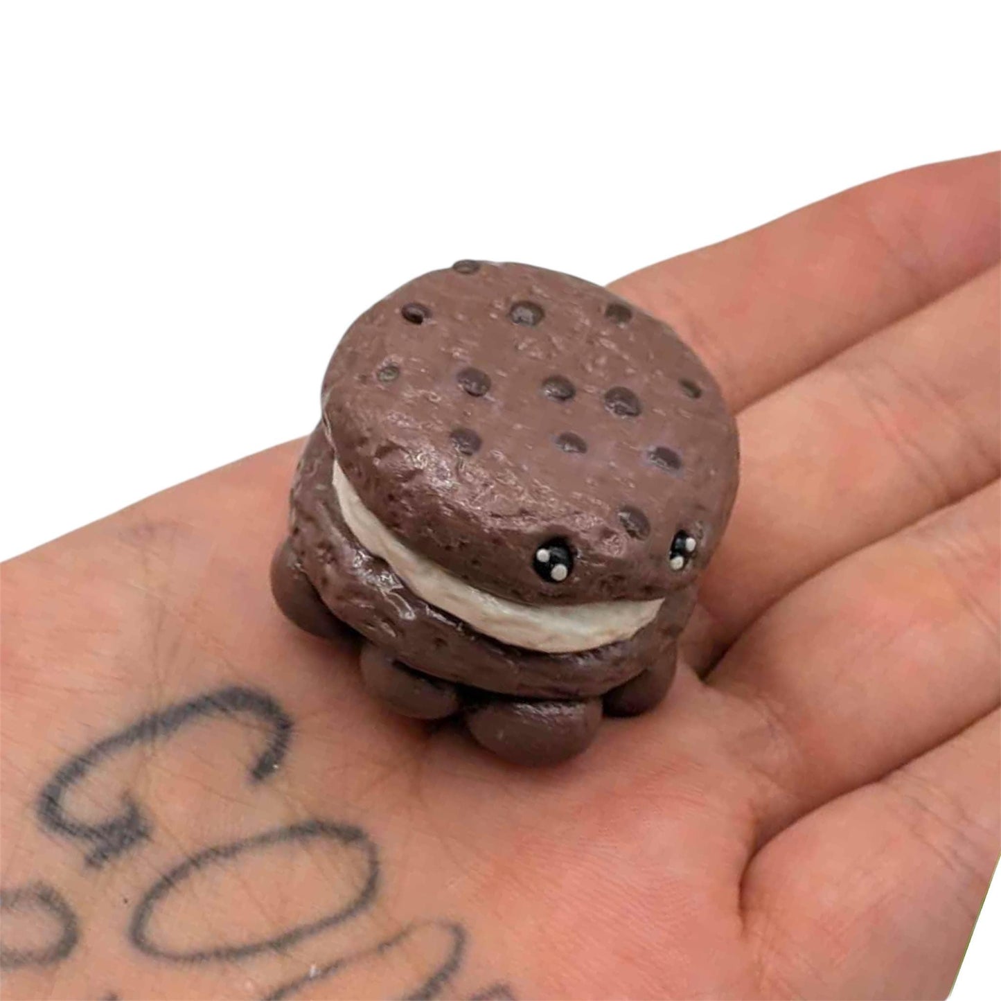 Miniature chocolate cookie sandwich on a hand with a white background