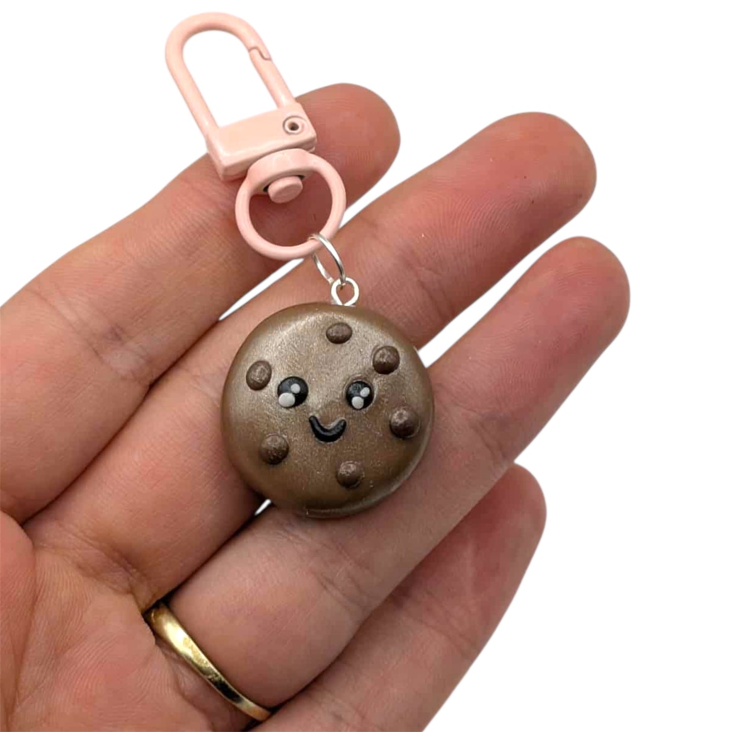 Cookie-shaped keychain with a pink clip held in a hand on a white background