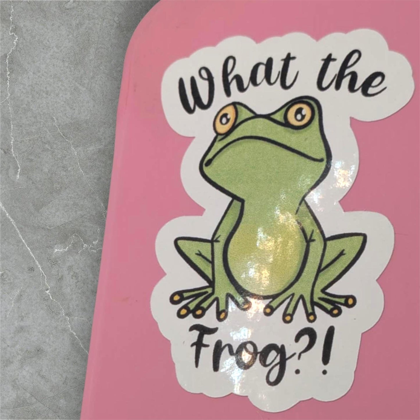 Sticker with a frog graphic and text 'What the Frog?!' on a pink background.
