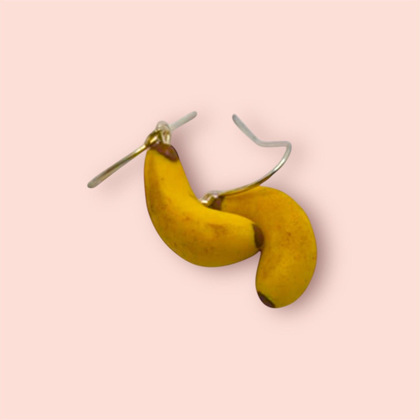 Banana-shaped earrings on a pink background