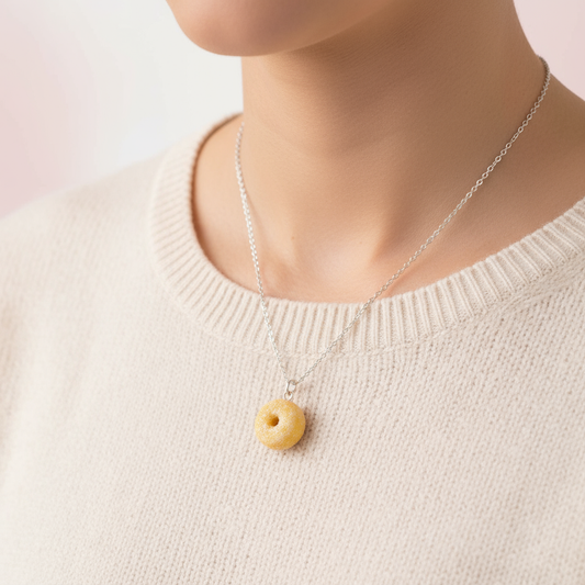 Handmade polymer clay donut necklace hung around woman’s neck 
