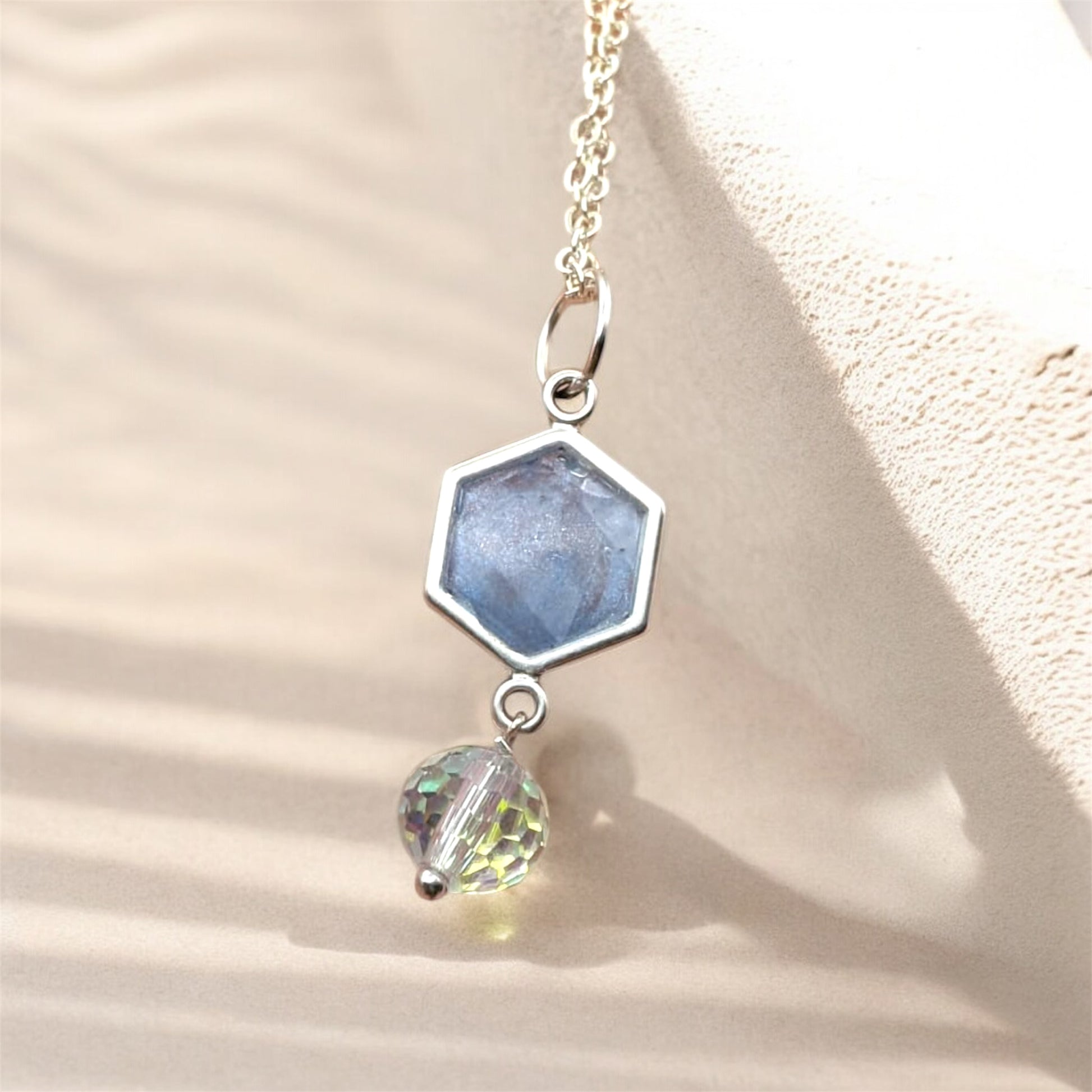 Necklace with hexagonal and round pendant on a beige background