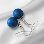 Blue berry earrings on a white fabric background
