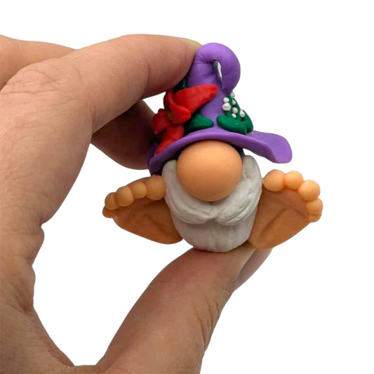 Hand holding a small gnome figurine with a colorful hat on a white background