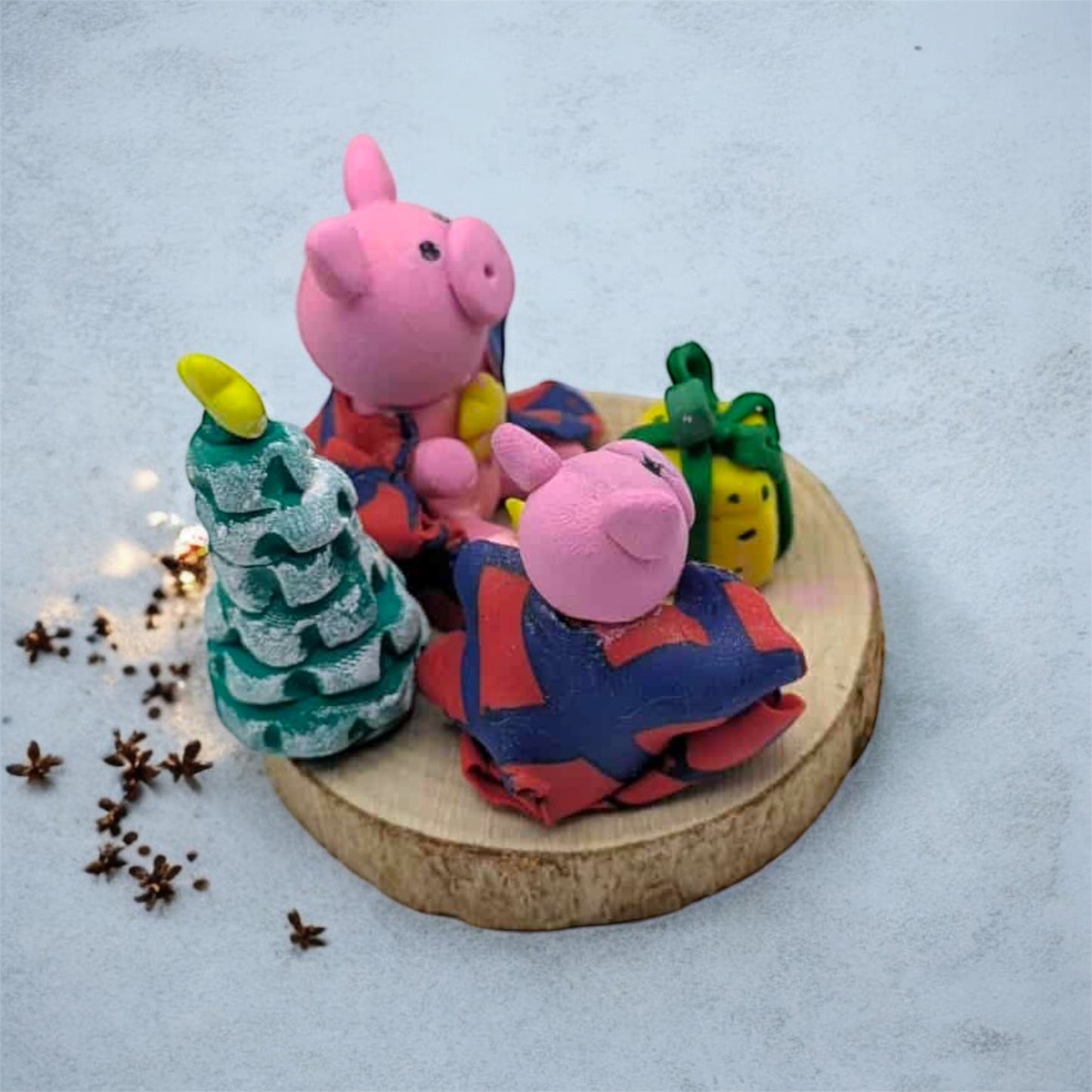Two pink pig figurines with colorful outfits on a wooden base with decorative elements.