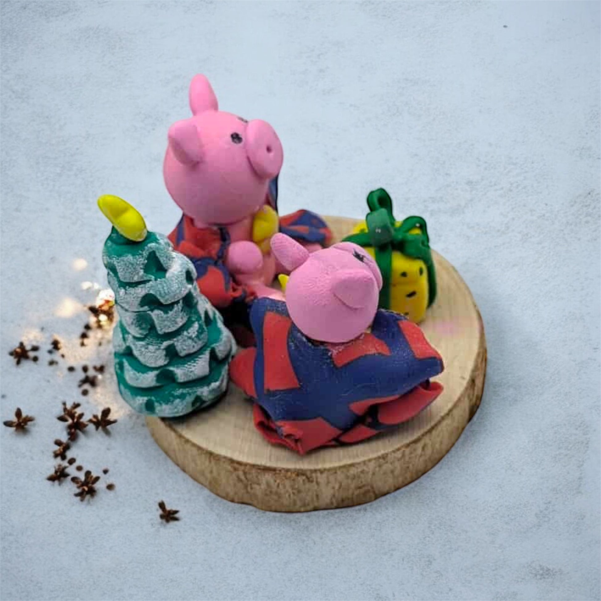 Two pink pig figurines with colorful outfits on a wooden base with decorative elements.