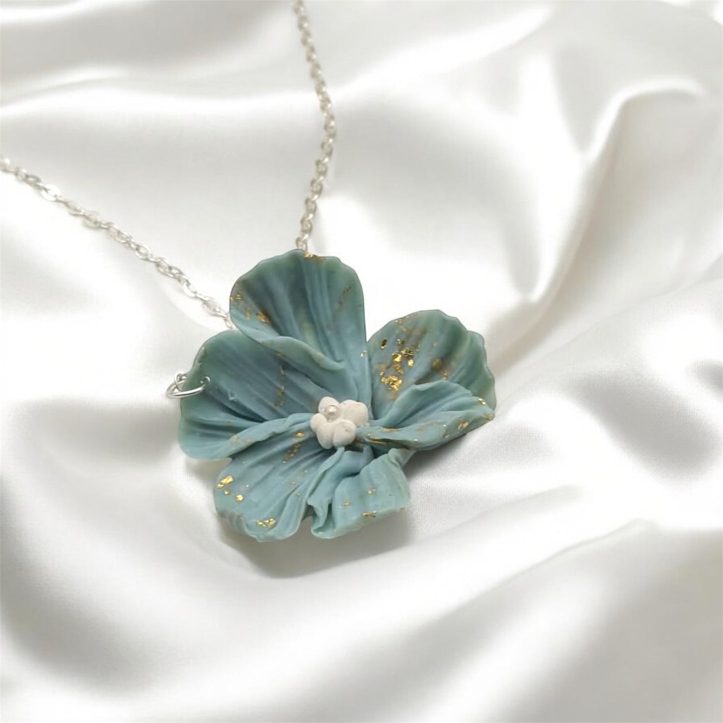 Blue flower-shaped pendant on a white satin background