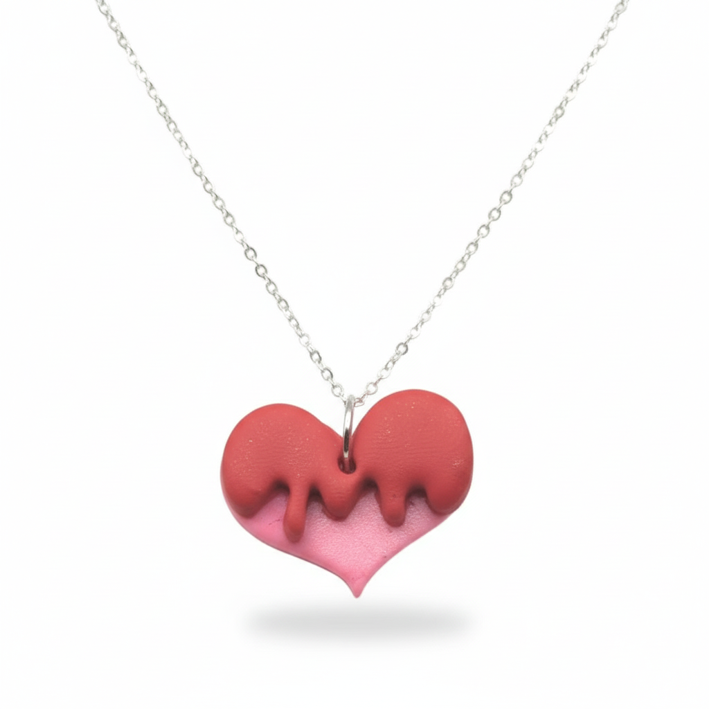Red and pink heart-shaped dripped pendant on a silver chain against a white background