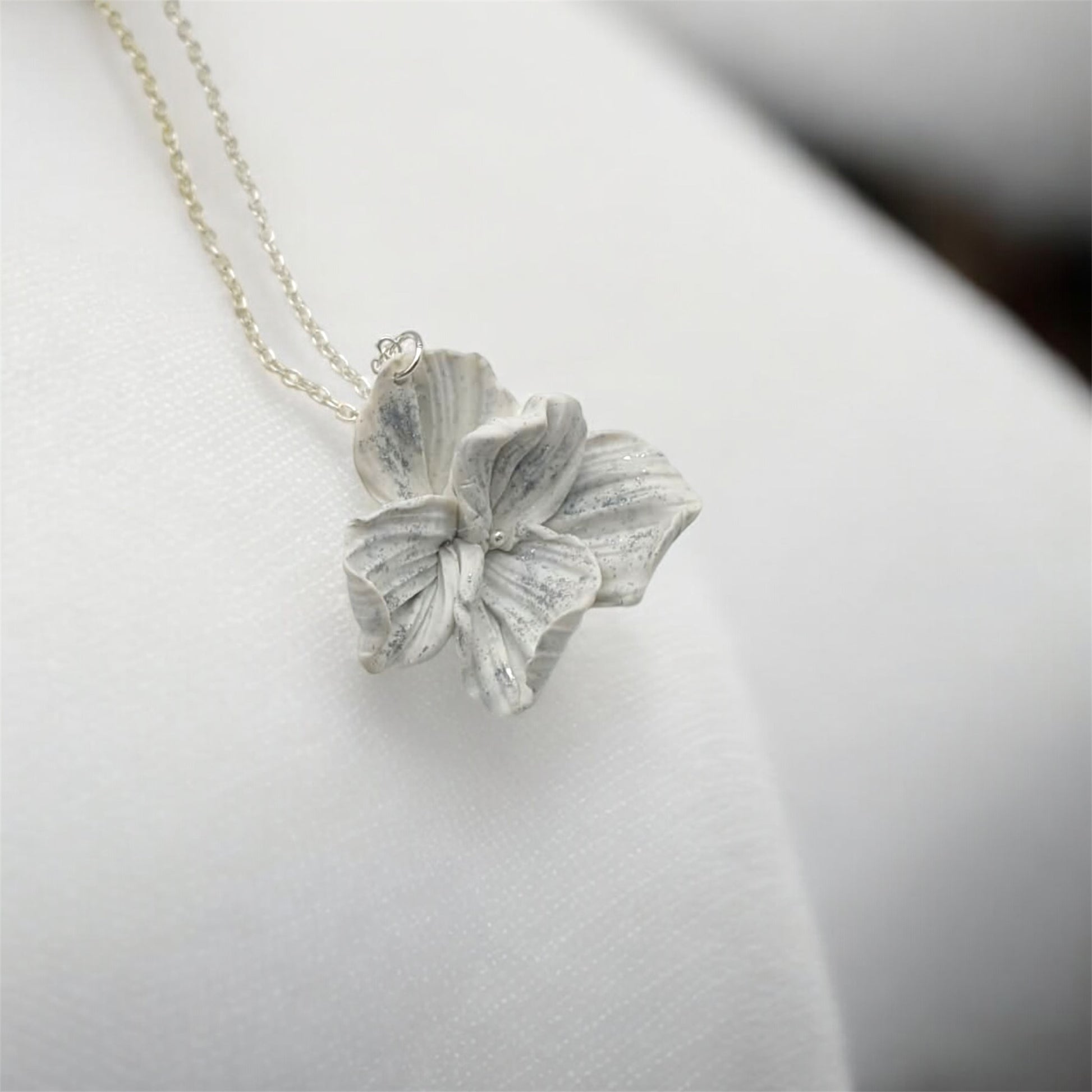Silver flower pendant necklace with realistic petals on white background