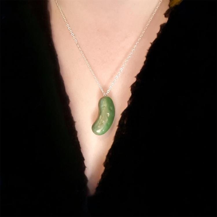 Green necklace pendant on a person wearing a black top
