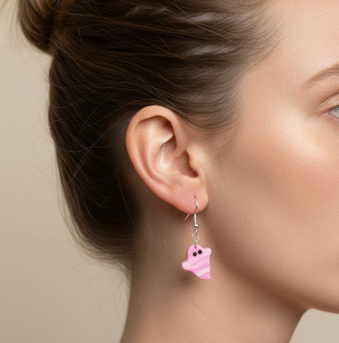 Close-up of a person wearing a pink ghost-shaped earring against a neutral background