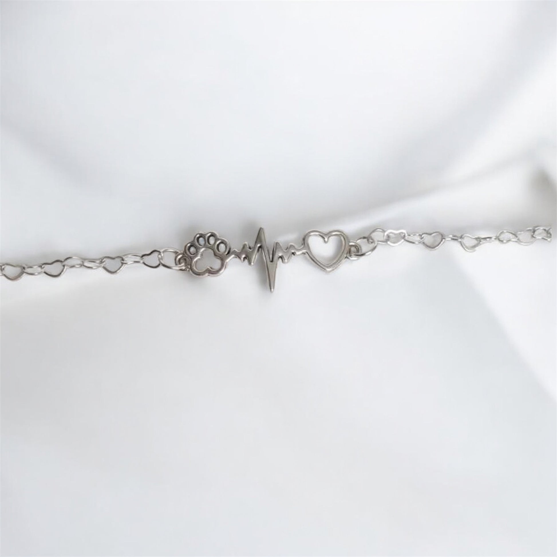 Paw bracelet featuring a silver paw print, heart charm, and heartbeat design, symbolizing pet love and companionship.