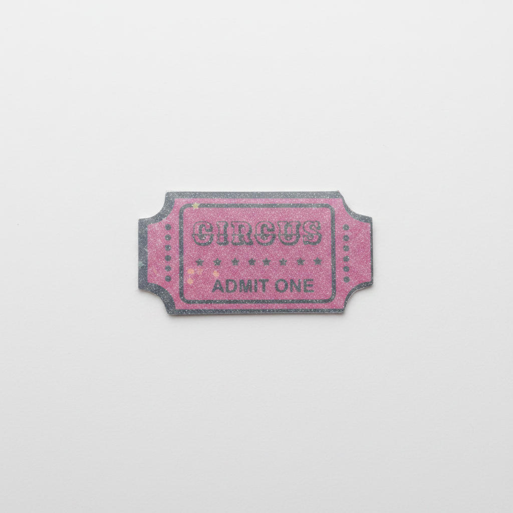 A pink glittery 'CIRCUS ADMIT ONE' ticket-shaped sticker with a dark glitter border, centered on a plain light grey background.