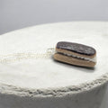 Chocolate eclair necklace on white background, angled view
