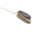 Chocolate eclair necklace held in hand showing scale