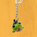 Kawaii Halloween frog keyring hanging, showing witch hat and pumpkin detail on orange background