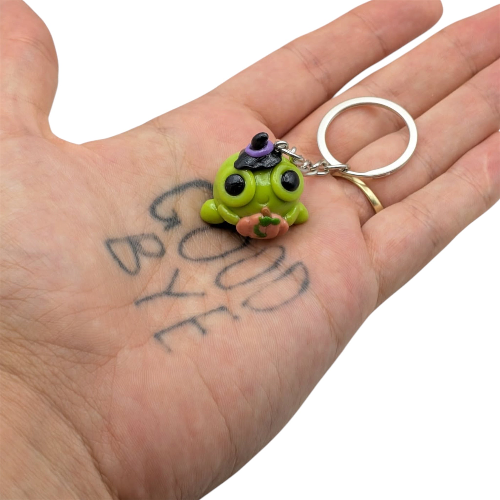Halloween frog keyring held in palm, showing coin-sized scale