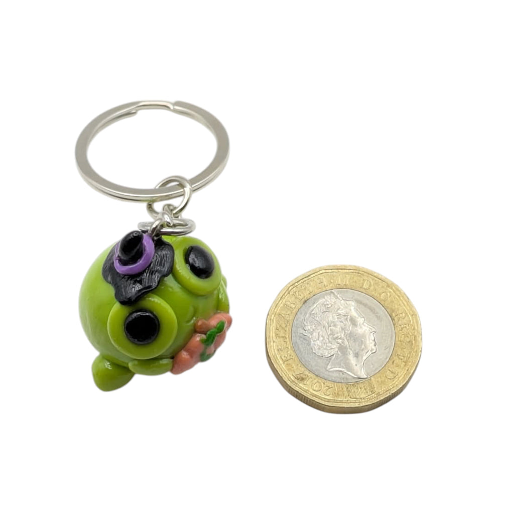 Polymer clay Halloween frog keyring next to a 1p coin showing size, white background