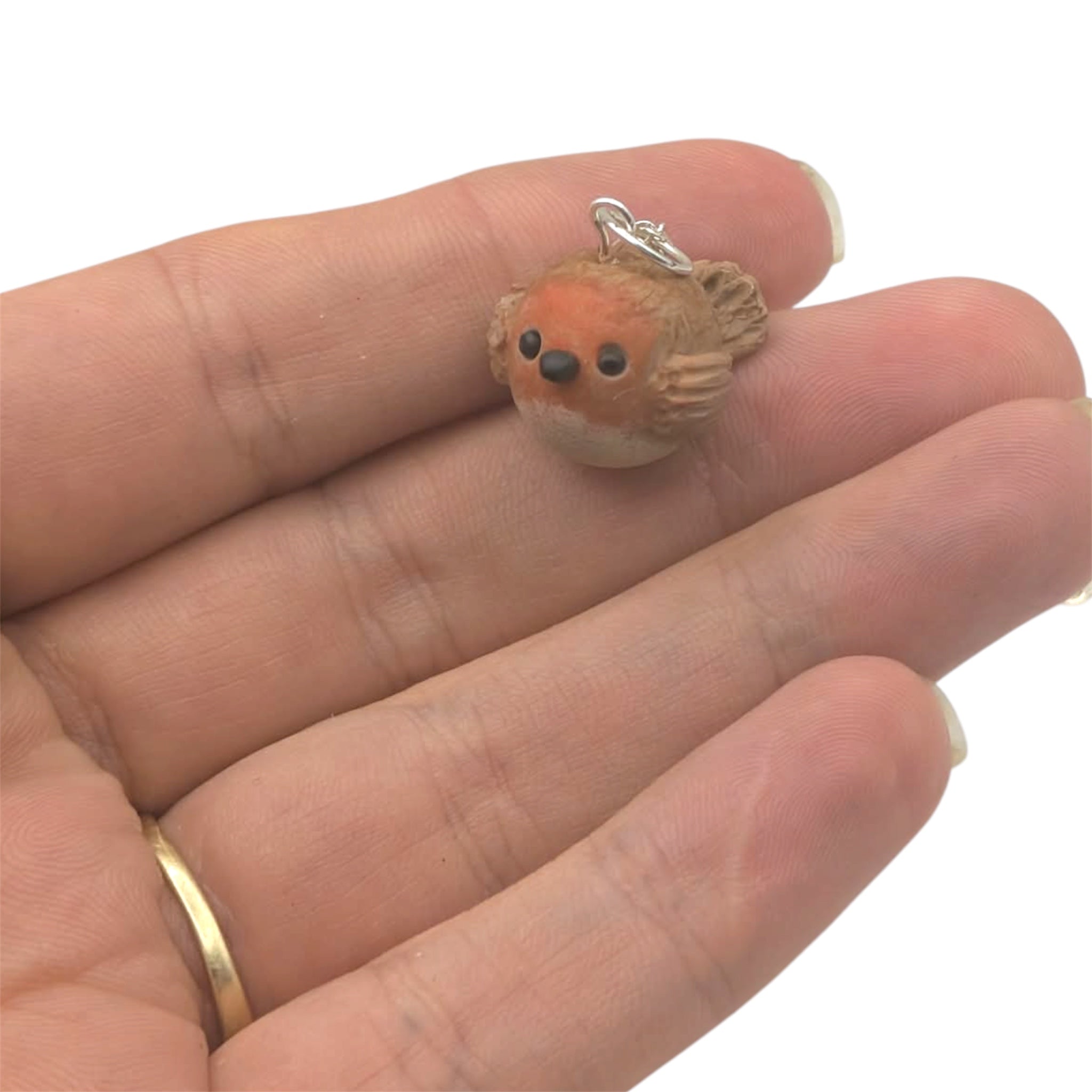 Tiny handmade robin bird pendant held in open palm showing scale