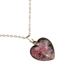 Heart-shaped pink resin pendant on a silver chain against a white background