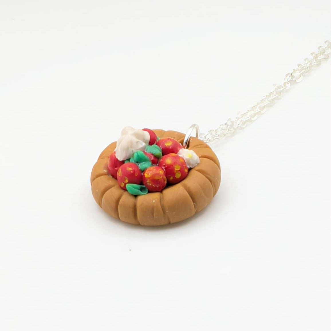 Side view of strawberry tart necklace on white background 