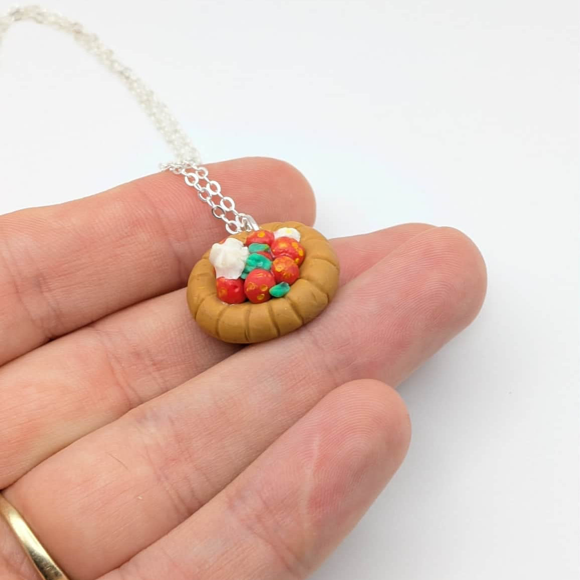 Polymer clay strawberry tart pendant held on hand on a white background 
