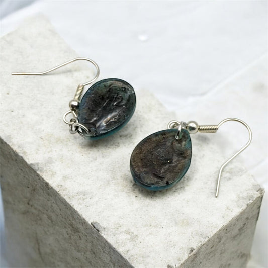 Pair of earrings with dark stone-like beads on a light background