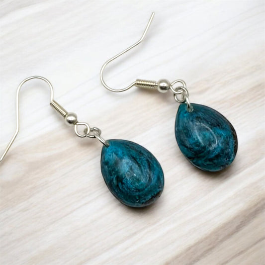 Teal marbled teardrop earrings on a light wooden surface