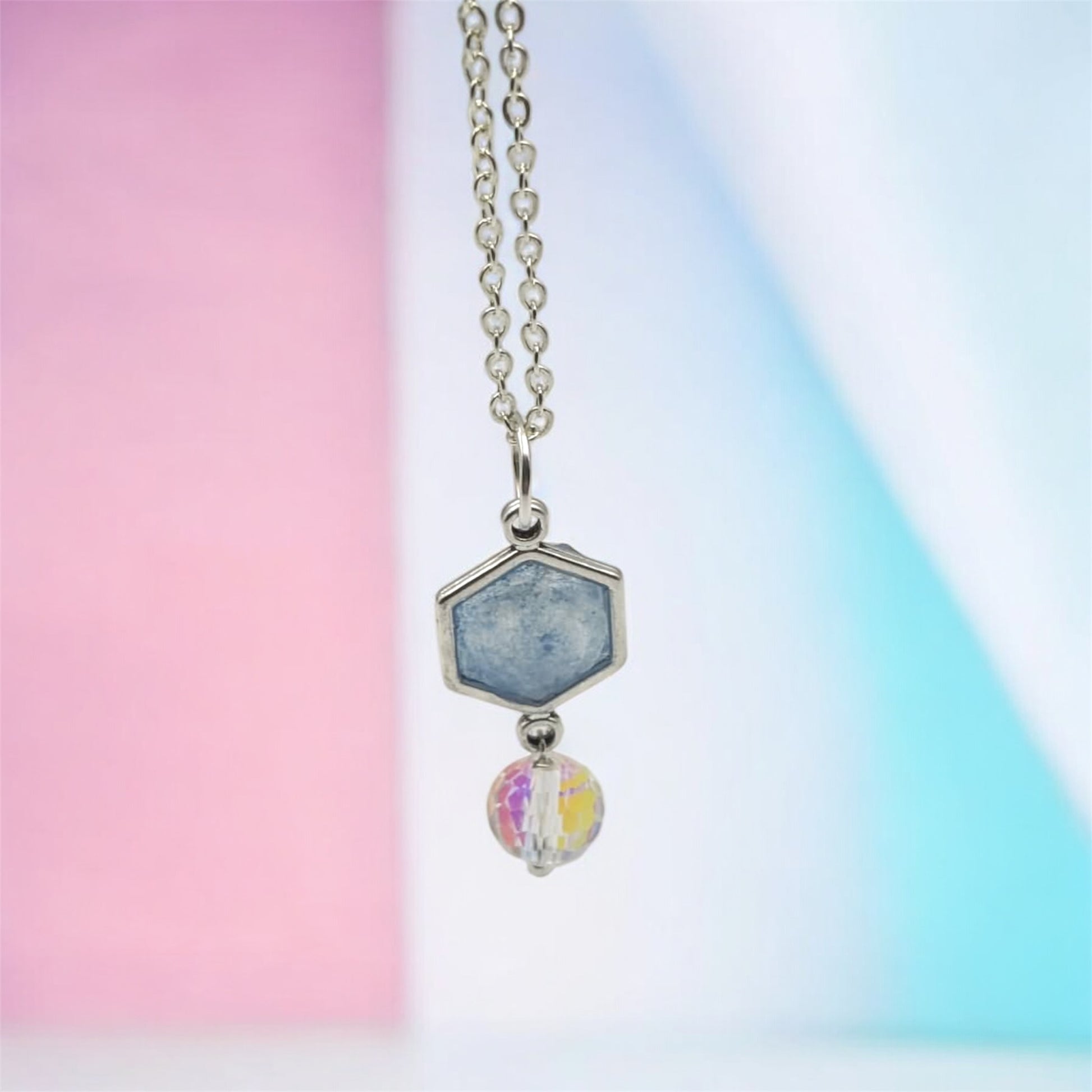 Necklace with a hexagonal pendant and colorful bead on a gradient background