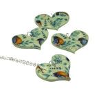 Nature pendant necklace with blue and orange birds and leaves on a green heart on a white background 