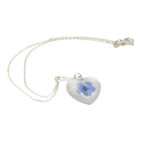 Heart-shaped necklace with a blue flower pendant on a white background
