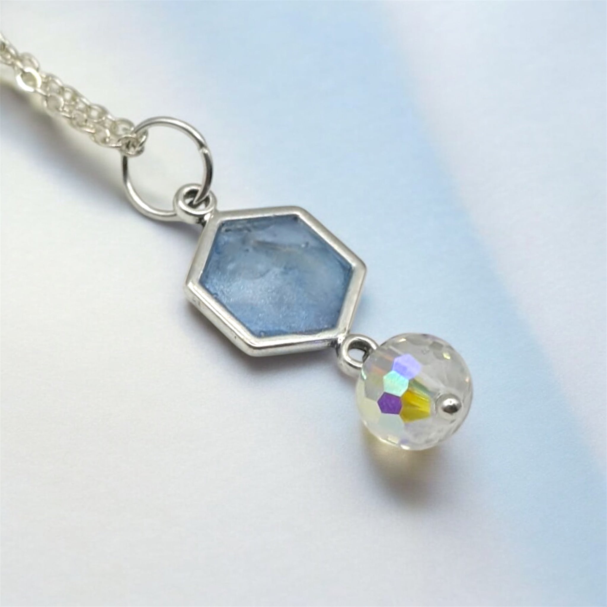 Necklace with hexagonal gemstone and round multicolored crystal on a light background