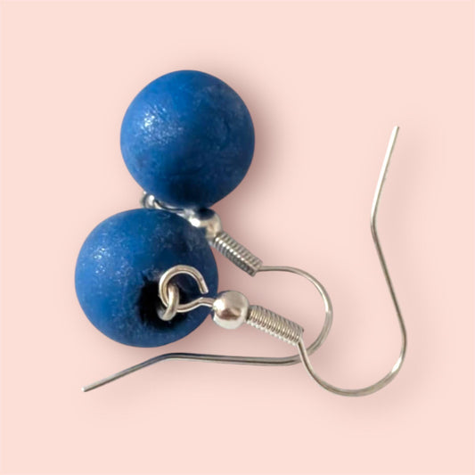 Blue round earrings on a pink background