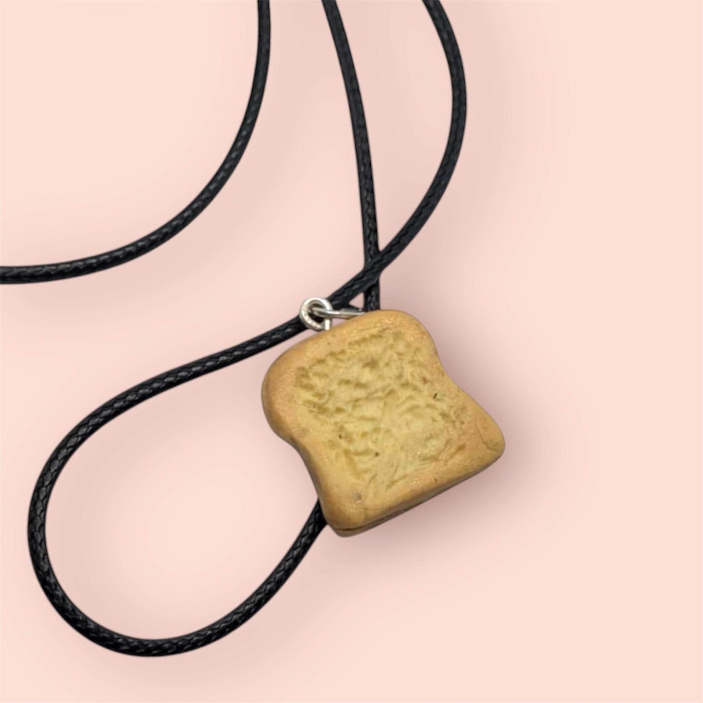 Back of necklace of a bread-shaped pendant on a pink background
