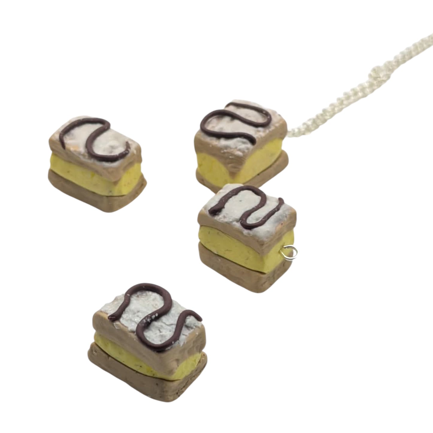 Miniature cake-shaped charm pendants with silver chain on a white background