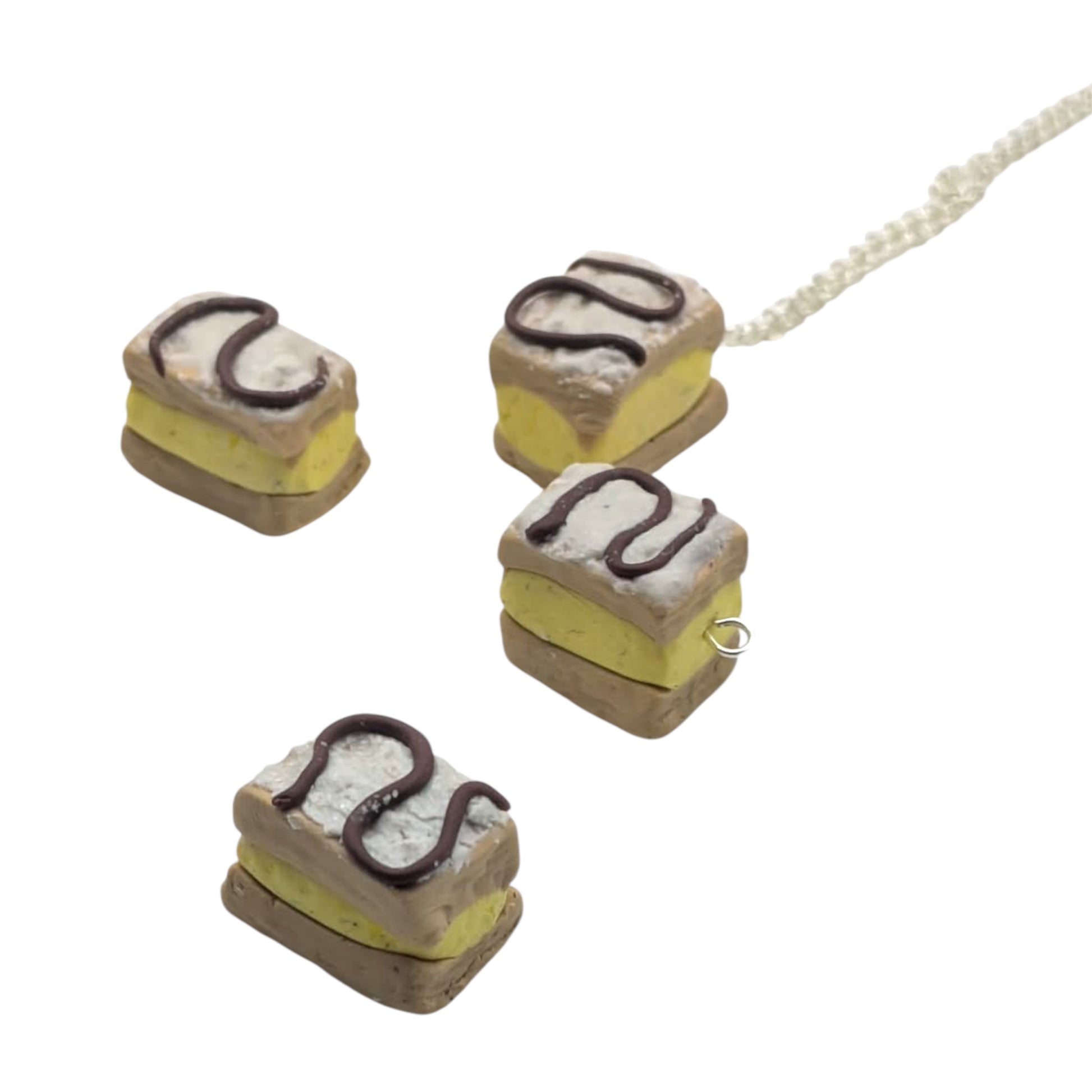 Miniature cake-shaped charm pendants with silver chain on a white background