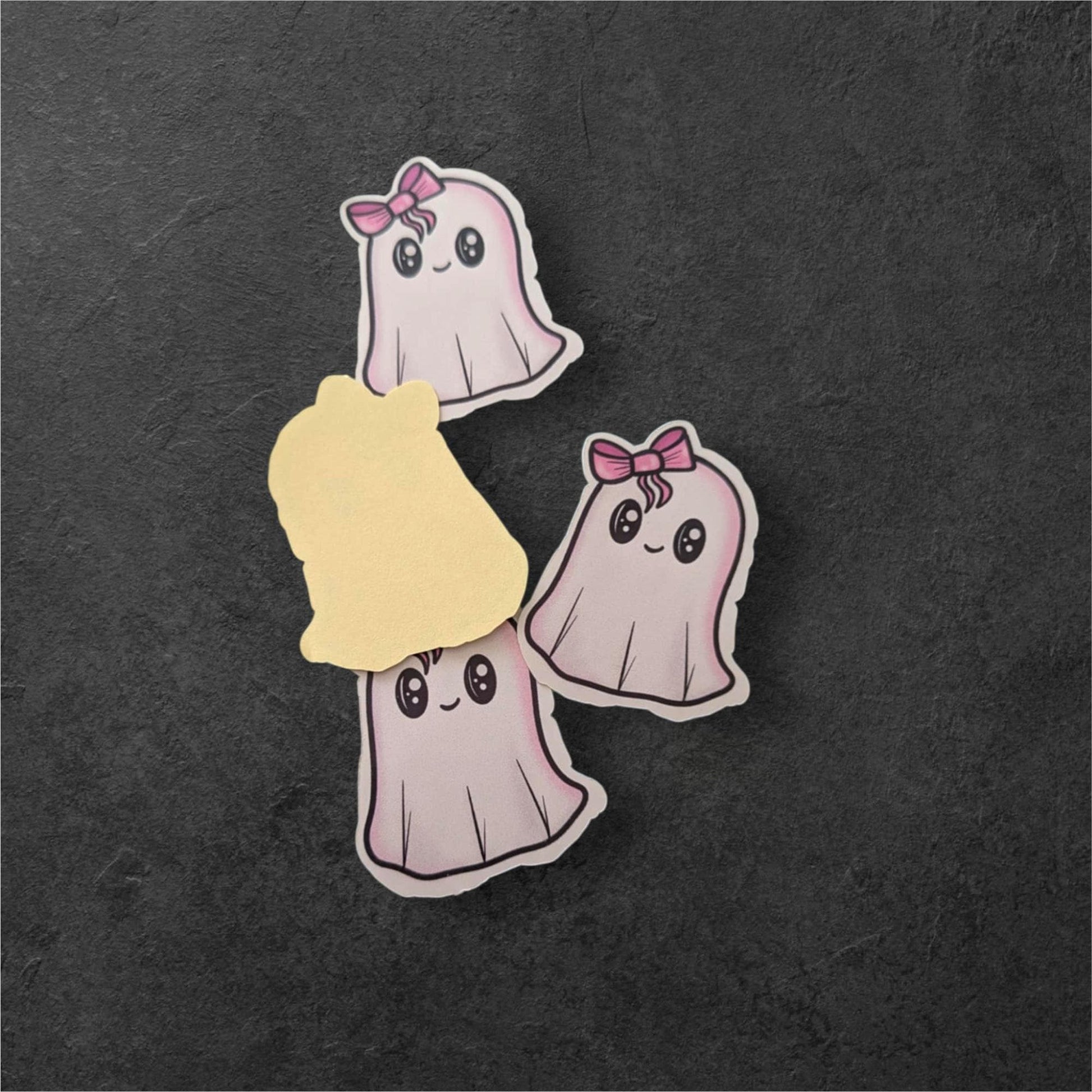 Three cartoon ghost pins with bows on a dark textured background
