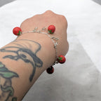 Bracelet with tomato charms on a wrist against a white background