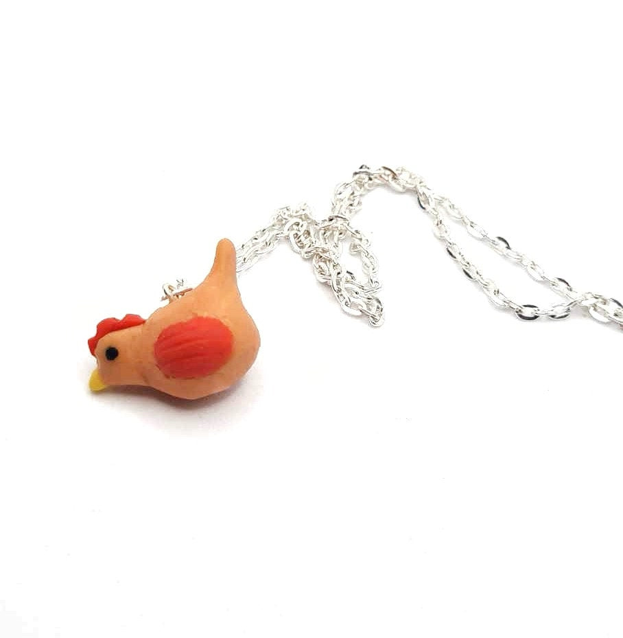Chicken-shaped pendant on a silver chain against a white background