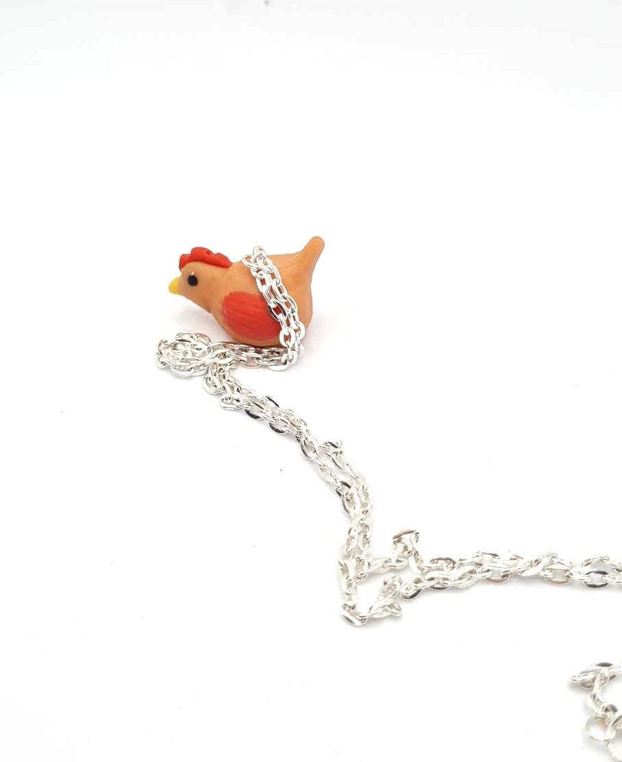 Silver chain with a rooster-shaped charm on a white background