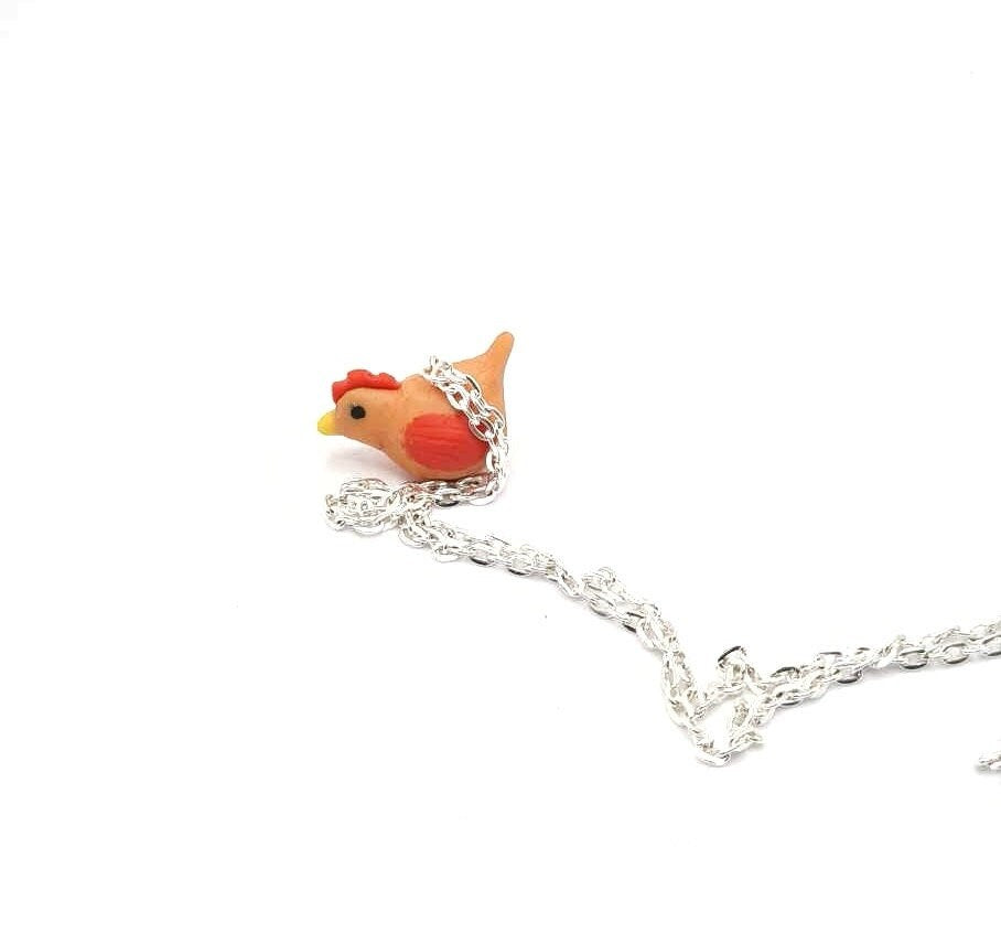Chicken-shaped pendant on a silver chain against a white background