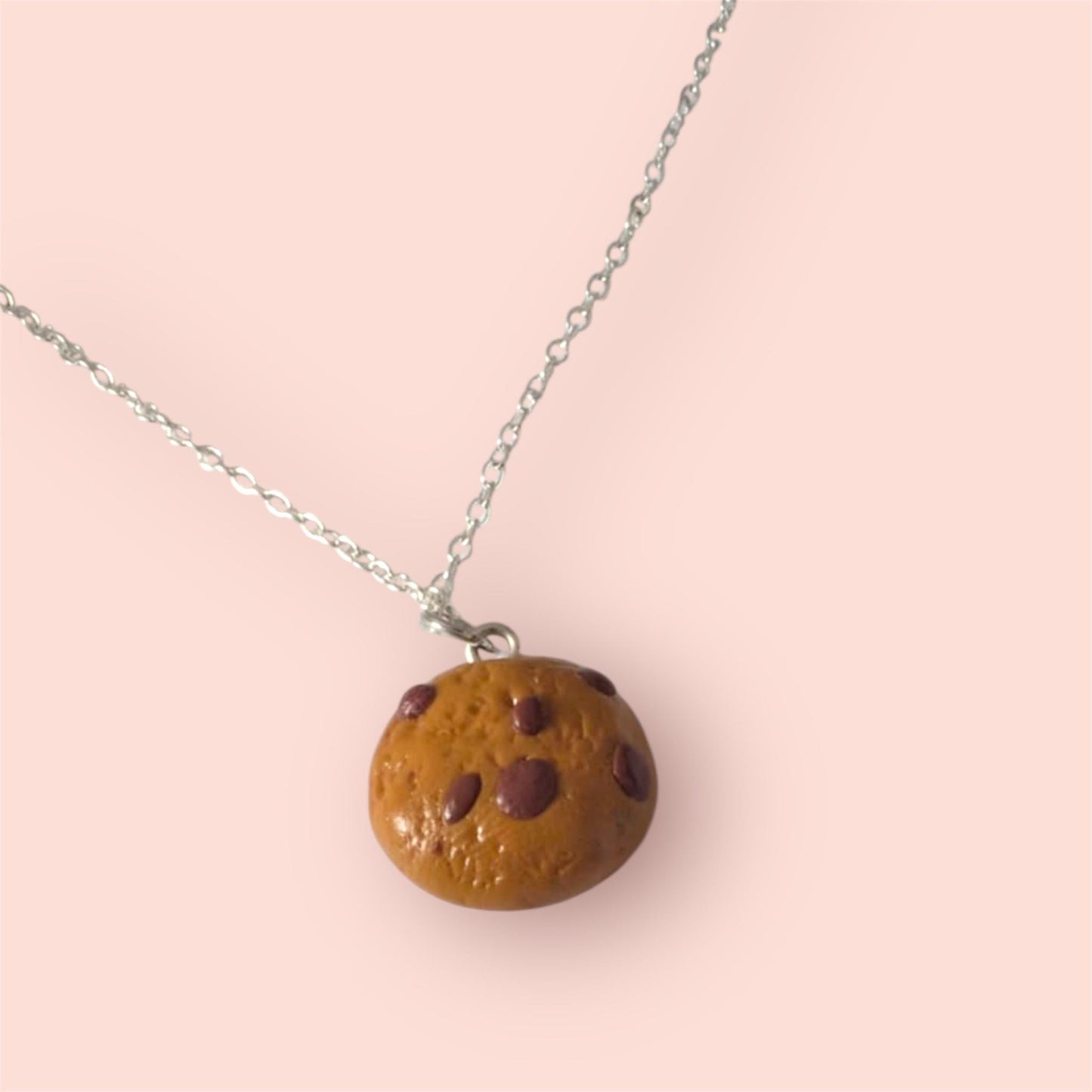 Necklace with a cookie-shaped pendant on a pink background