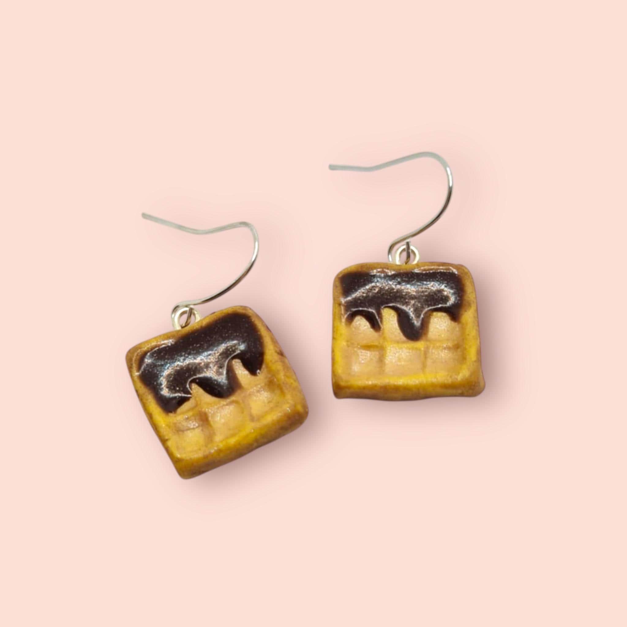 Waffle-shaped earrings on a pink background
