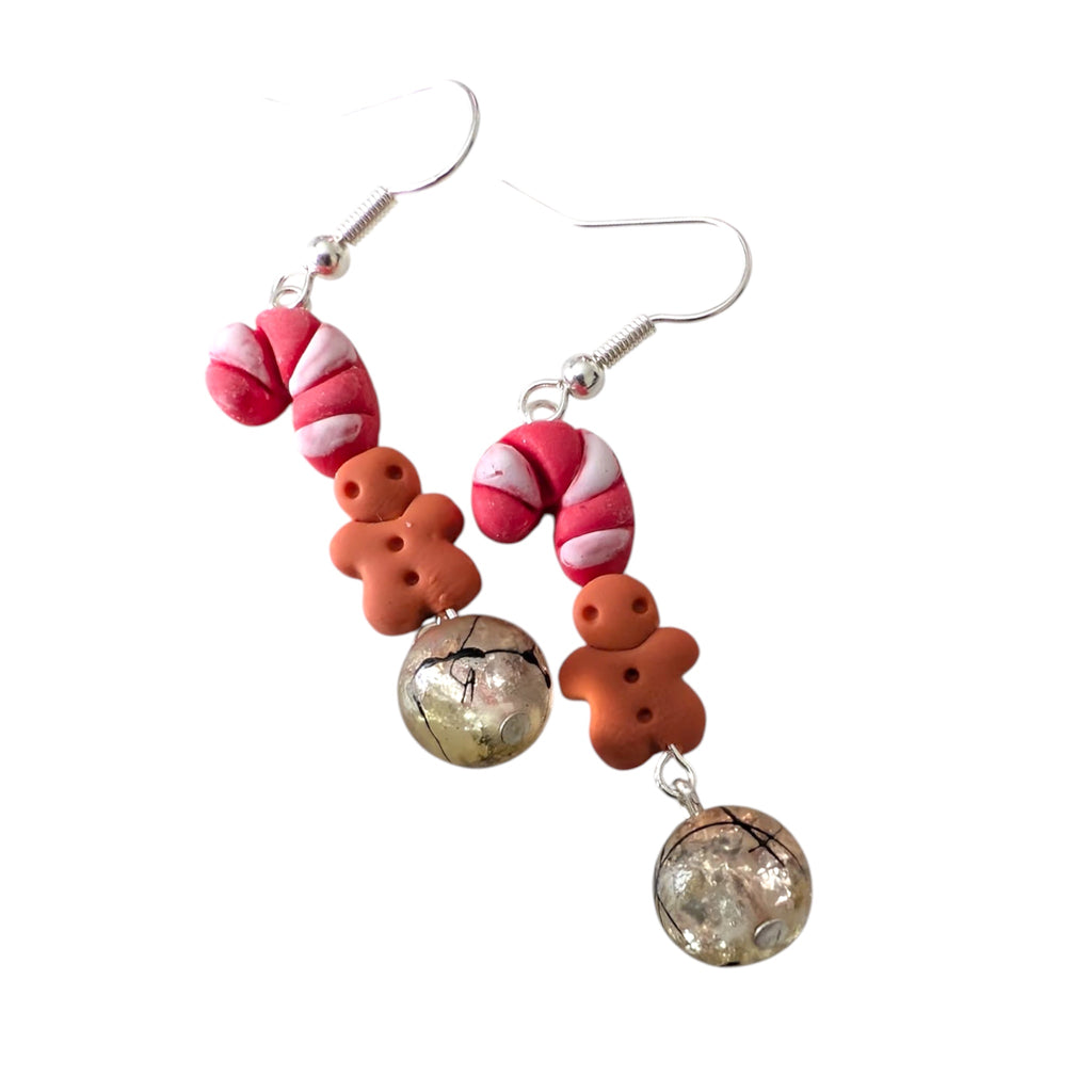 Pair of earrings with candy cane and gingerbread man design on a white background