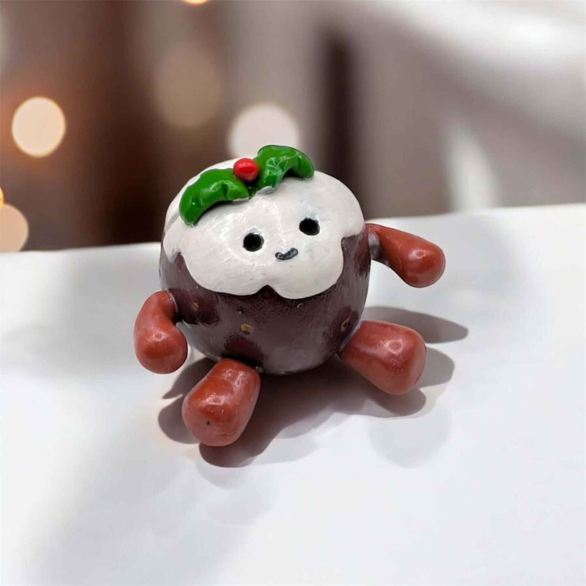 Small decorative figure of a Christmas pudding with a happy face on a white surface.