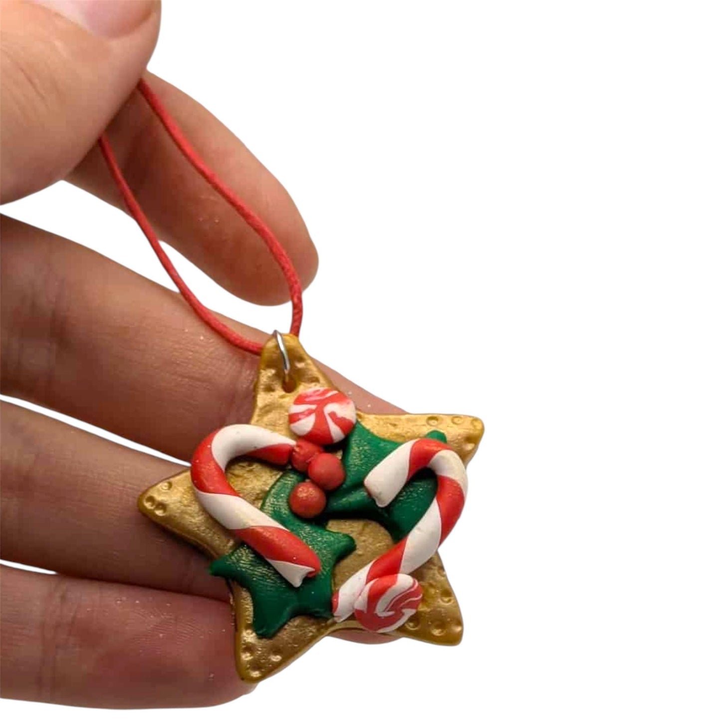 Hand holding a star-shaped Christmas ornament with candy cane design on a white background