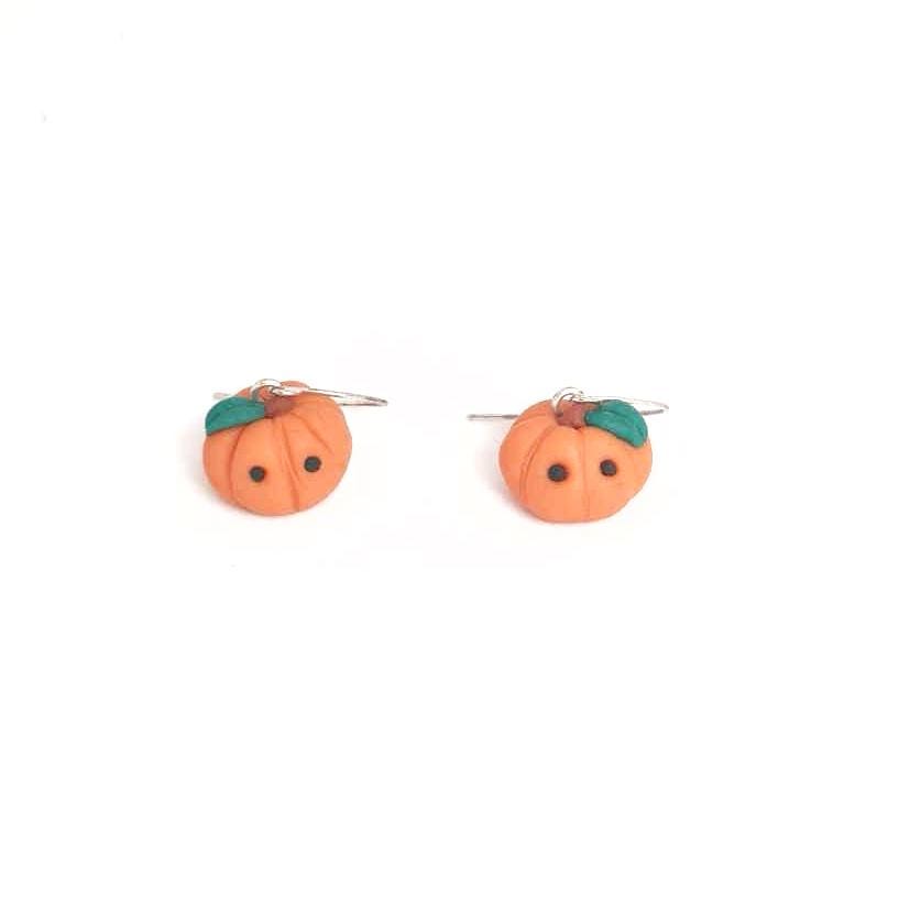 Pumpkin-shaped earrings with green leaves on a white background