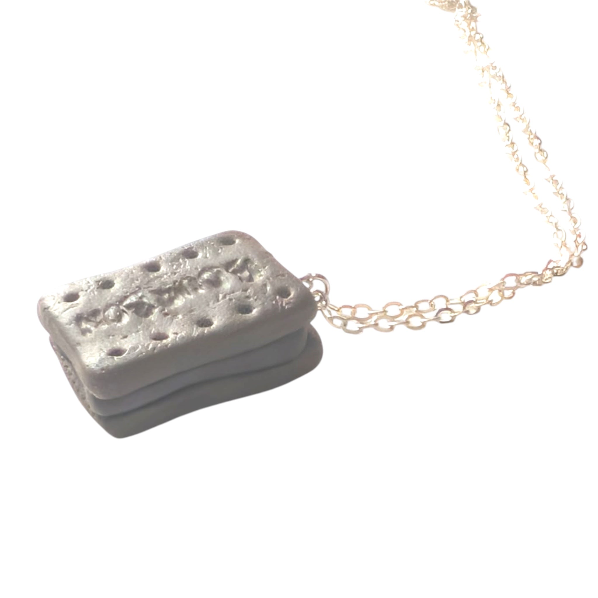 Close up of bourbon polymer clay biscuit pendant, showing chocolate filling and silver chain finish