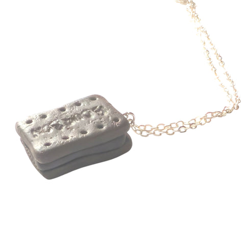 Close up of bourbon polymer clay biscuit pendant, showing chocolate filling and silver chain finish